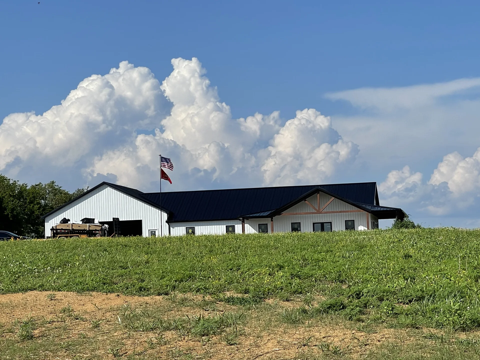 Long building with a metal roof in an open grassy setting